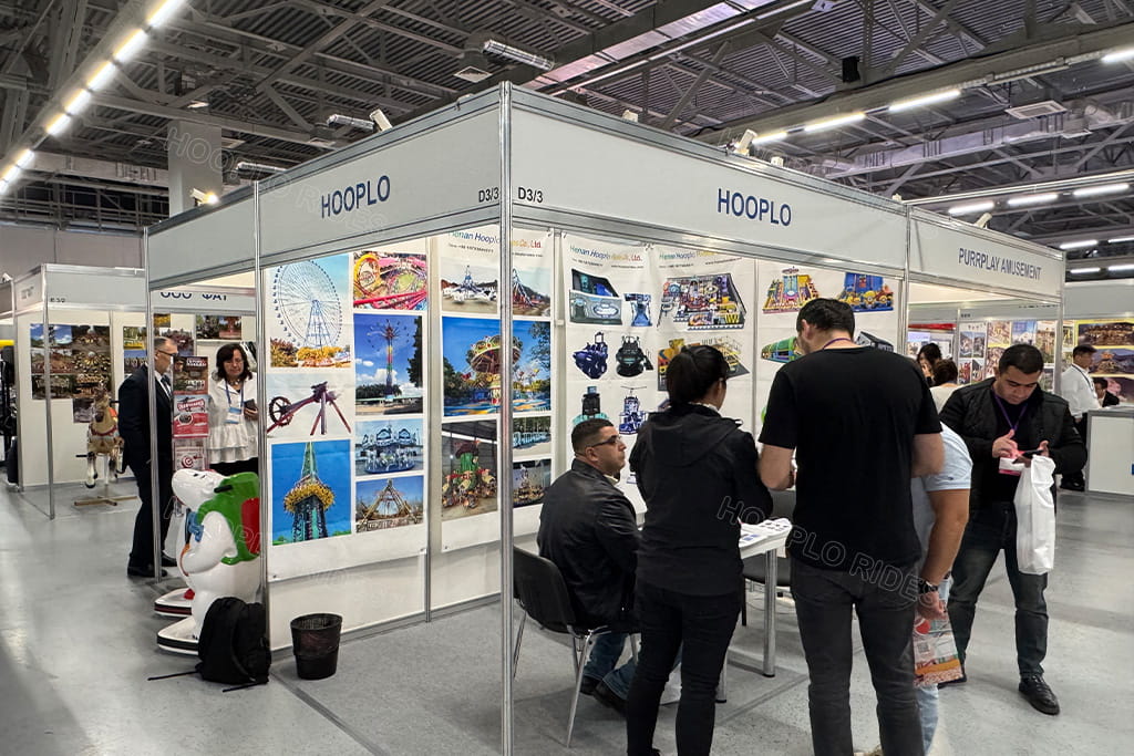 On-site photo of Hooplo booth at 2025 Russia Autumn Amusement Fair, outdoor & indoor amusement rides manufacturer exhibition stand with foreign clients consultation